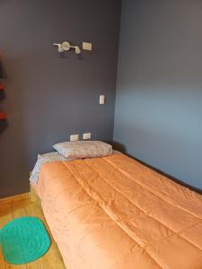 1 dormitorio con 1 cama con colcha de color naranja en Aires de Asturias, en Puerto Montt