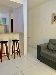 uma sala de estar com um sofá e dois bancos de bar em Flat Barra do Cunhaú em Canguaretama