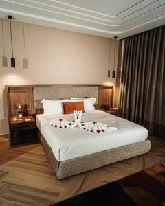 a bedroom with a large white bed with decorations on it at City Hotel by Waves in Kenitra