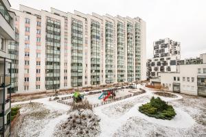 un patio cubierto de nieve frente a un gran edificio en Praga Sulejkowska Comfort Apartment en Varsovia
