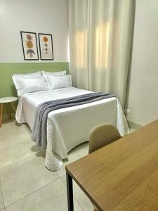 a bedroom with a white bed and a table at Roma Flats in Campo Novo do Parecis