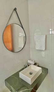 a white bathroom with a sink and a mirror at Roma Flats in Campo Novo do Parecis