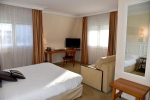 a hotel room with a bed and a desk at The Originals City, Hôtel Chantecler, Le Mans in Le Mans