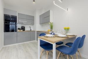 a kitchen with a wooden table and blue chairs at Dark Blue and Grey Apartment with Pastel Bedroom in Warsaw by Renters in Warsaw