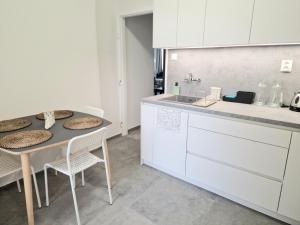 a kitchen with white cabinets and a table and chairs at Princ next to President Palace in Bratislava