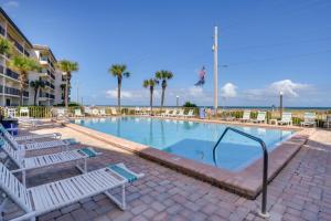 a swimming pool with lounge chairs and the ocean at Oceanfront Ormond Beach Condo Community Perks! in Ormond Beach
