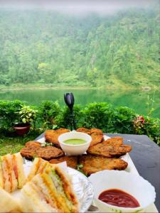 a plate of food with sandwiches and dipping sauce at Allure lake front in Nainital
