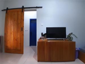 a television on a wooden stand next to a blue door at anik homestay & dormy Batukaras in Batukaras