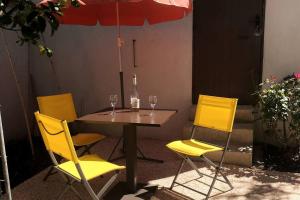 una mesa con tres sillas amarillas y una sombrilla en studio au pied des troglodytes, près de la plage, en Saint-Chamas