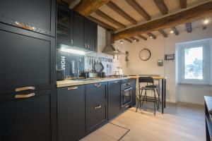 una cocina con armarios negros y una barra con taburete en MaRì Modern Flat - Nel cuore verde di Perugia - Posto Auto, en Perugia