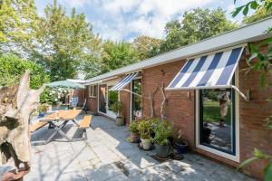 a patio with a blue and white awning and plants at Zoomgronden Renesse in Renesse