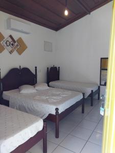 a group of three beds in a room at Pousada Flores da Terra in Paraty