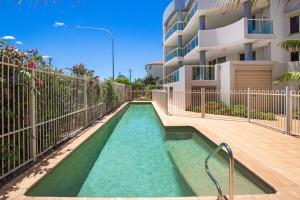 une piscine en face d'un bâtiment dans l'établissement Riviera 203, à Port Macquarie