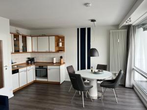 eine kleine Küche mit einem weißen Tisch und Stühlen in der Unterkunft Ferienwohnung Fördedeck in Kiel