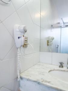 un teléfono blanco en el baño con lavabo en Momax Hotel, en Marília