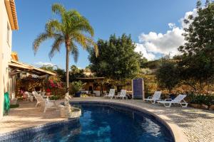 a swimming pool with chairs and a palm tree at Le jardin de Teresa in Algoz