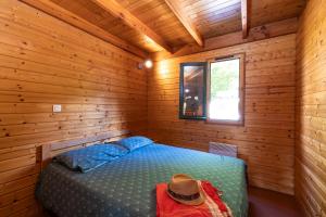 1 dormitorio con 1 cama en una cabaña de madera en Camping Le Lac des Sapins, en Cublize