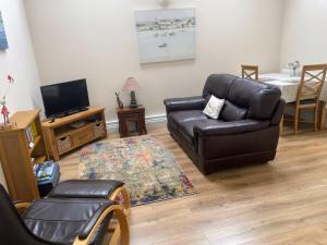 sala de estar con sofá de cuero y TV en The Snicketts, en Ludlow