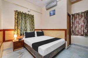 a bedroom with a bed and a lamp and curtains at SPOT ON Benaka Delux Lodging & Delux Rooms in Bangalore