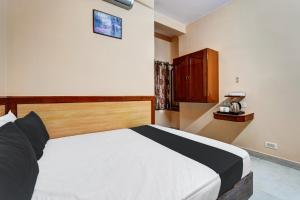a bedroom with a large bed with a wooden headboard at SPOT ON Benaka Delux Lodging & Delux Rooms in Bangalore