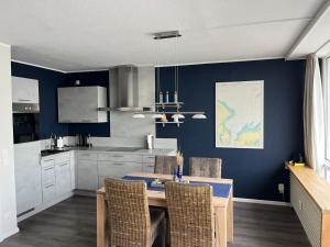 eine Küche mit einem Tisch und einer blauen Wand in der Unterkunft Ferienwohnung Panoramadeck in Schilksee