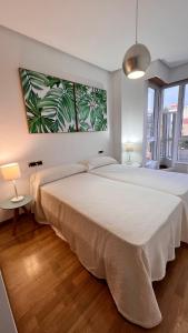 a bedroom with two beds and a painting on the wall at Apartamentos San Martin Ourense Centro 2 in Ourense