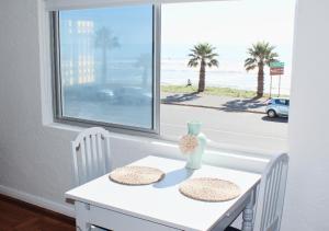 a white table with two chairs and a window with a view of the beach at Villa Capri in Cape Town