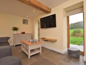 een woonkamer met een bank en een tv aan de muur bij 2 Bed in Chulmleigh 72791 in Coldridge