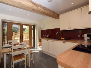 een keuken met witte kasten en een houten tafel bij 2 Bed in Chulmleigh 72791 in Coldridge