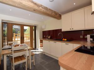 a kitchen with white cabinets and a wooden table at 2 Bed in Chulmleigh 72791 in Coldridge