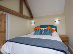 een slaapkamer met een bed met blauwe en oranje kussens bij 2 Bed in Chulmleigh 72791 in Coldridge