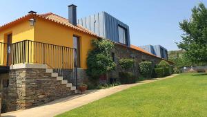 una casa amarilla con una pared de piedra en Quinta dos Avidagos AgroTurismo Mirandela en Mirandela