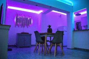 a dining room with purple lighting and a table and chairs at Jolie villa loc-saisonnière - la petite cocagne in Alleins