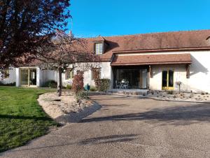 a white house with a tree and a driveway at Ferme de la NOE in Sérigny