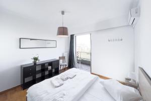 a bedroom with a white bed and a large window at Urban Apartment in the Heart of Athens in Athens