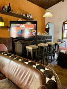 a living room with a tv and a bar with stools at Guaru Surf Hostel in Guarujá