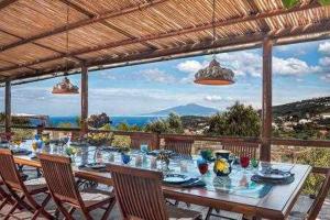 stół jadalny z krzesłami i widokiem na ocean w obiekcie GOCCE VILLAS - Antica Limonaia w mieście Massa Lubrense