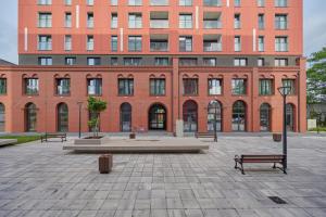a large brick building with benches in front of it at New Studio Tęczowa with FREE GARAGE Wrocław by Renters in Wrocław