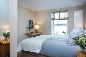 a white bedroom with a bed and a window at Western Court Sidmouth close to town and beach in Sidmouth