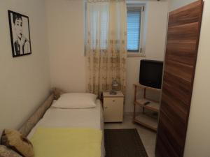 a small bedroom with a bed and a television at Apartments Lička 25 in Split