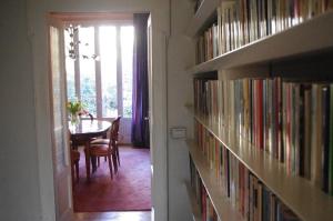 a hallway with bookshelves and a dining room with a table at Teodora B&B in Milan