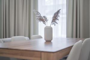a white vase with a plant sitting on top of a table at Laurinska 1 Apartments in Bratislava