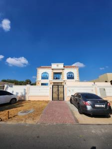 a house with a car parked in front of it at Small single room inside luxurious villa in Dubai