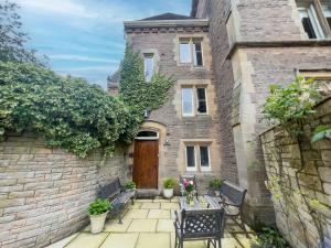 a brick house with two benches and a wooden door at Geltsdale East Wing in Carlisle