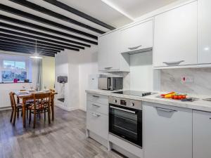 a kitchen with white cabinets and a dining table at 2 Bed in Betws-y-Coed 78601 in Llanddoget