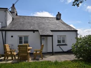 a white house with chairs and a table in front of it at 2 Bed in Betws-y-Coed 78601 in Llanddoget