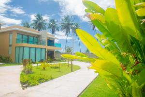 a building with palm trees in front of it at Na Morada dos Milagres, condomínio Morada do Toque in São Miguel dos Milagres