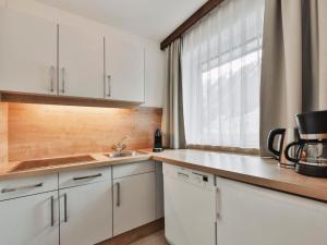 eine Küche mit weißen Schränken, einem Waschbecken und einem Fenster in der Unterkunft Apartment Chalet Sofie-2 by Interhome in Ischgl
