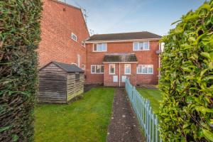 una casa de ladrillo con una valla y un pequeño cobertizo en Stylish short-term let in Bucks en Loudwater