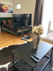 a living room with a vase of flowers and a tv at Kölner City Stillvolle Apartment in Cologne